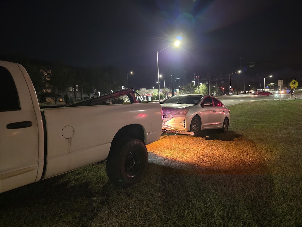 Night tow — white wrecker towing a Hyundai under streetlights